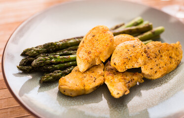 cooked dish. Chicken nuggets with green asparagus on plate