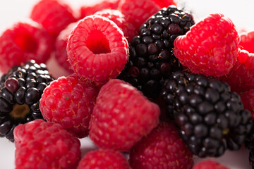 handful of raspberry and blackberry berries on white background