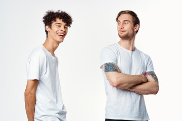 Two cheerful friends in white t-shirts stand side by side cropped view