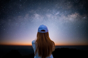 Silhouette of young woman looking beautiful view of night sky and star and milky way alone on top...