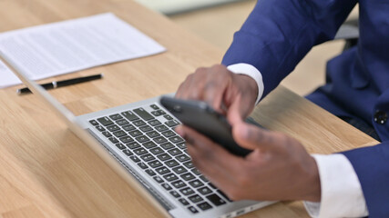 Close up of African Businessman using Smartphone and Laptop