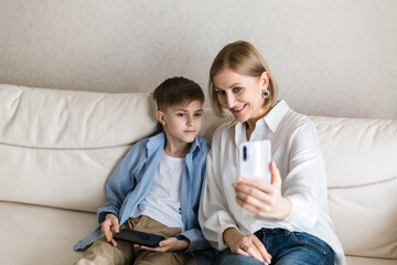 Boy and adult woman take a selfie on the phone while sitting on the couch.