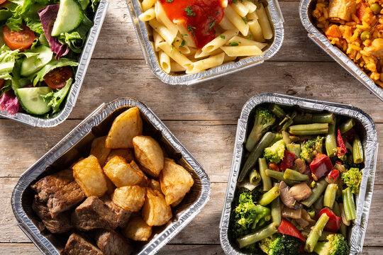 Take away healthy food in foil boxes on wooden table