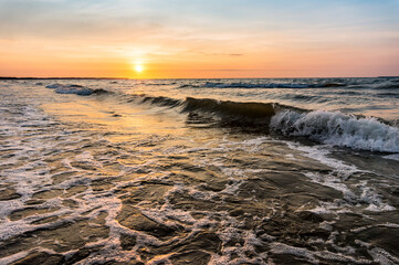 Obraz premium Sunset over the sea. Reflection of sunlight in the sea waves. Red and yellow sky in the rays of the sunset.