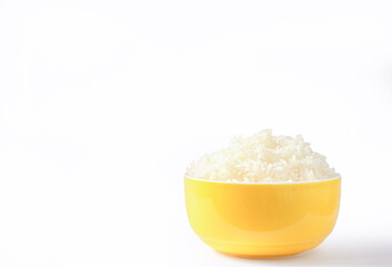 Warm steamed rice, freshly cooked in a yellow bowl on a white background, is a staple food Asian staple food with valuable fiber and nutrients with copy space for text.
