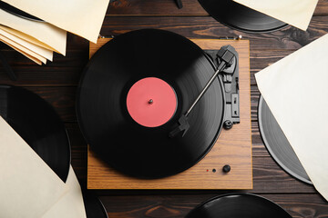 Modern player and vinyl records on wooden background, flat lay