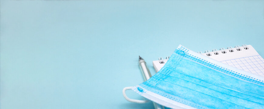 Medical Mask And Notepad On Blue Background. Stationery Items And Sanitary Mask.