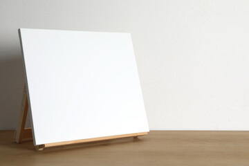 Wooden easel with blank canvas on table. Space for text