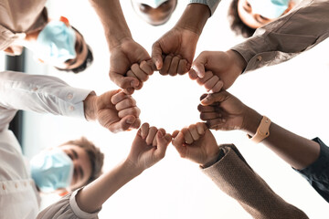 Portrait of diverse people in masks giving fist bump in cirle