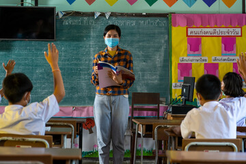 Group of Asian elementary school students and teacher wearing hygienic mask to prevent the outbreak of Covid 19 in classroom,Elementary school,Learning and health care concept.