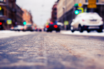 Snowy winter in the big city, the cars traveling on a green traffic light signal. Close up view from the asphalt level