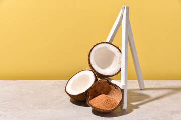 coconut sugar in a nut shell with coconut halves on a stone table on a yellow background