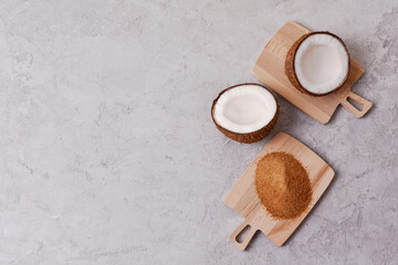 coconut sugar on wooden board together with coconut on gray concrete background with copy space