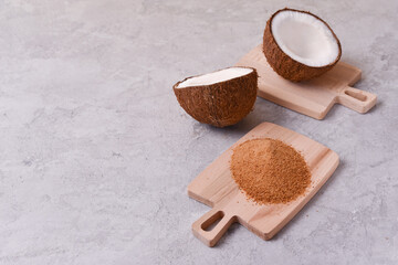 coconut sugar on wooden board together with coconut on gray concrete background with copy space