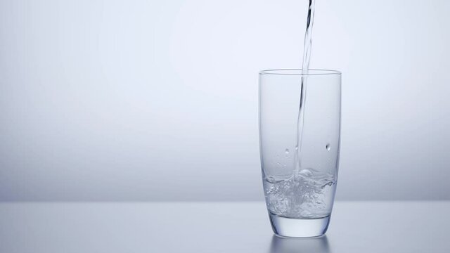 Clean drinking water pours into the glass. A light background with a copy of the space.