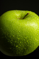 Green apple with water drops on black background