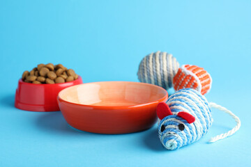 Feeding bowls and toys for pet on light blue  background