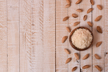almond flour in a wooden bowl on a white wooden table with nuts with copy space