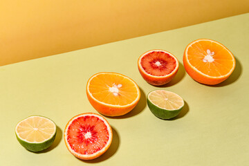 citrus fruits cut in half in a row on a yellow-green background with copyspace