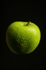 Green apple with water drops on black background