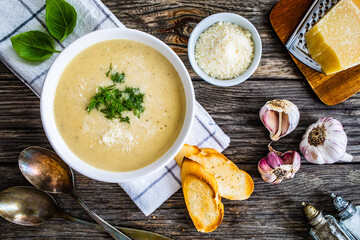 Cream garlic and parmesan soup on wooden table
