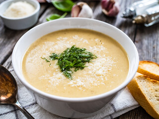 Cream garlic and parmesan soup on wooden table
