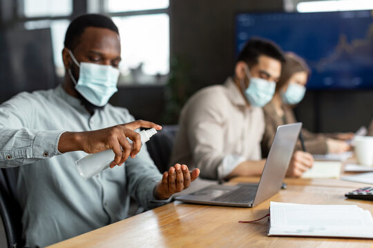 International workers wearing medical masks using sanitizer