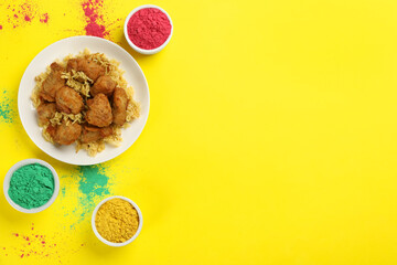 Traditional Indian food and color powders on yellow background, flat lay with space for text. Holi festival celebration