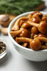 Tasty marinated mushrooms in bowl on grey table, closeup
