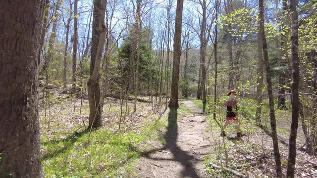 Hiking a path in mid spring following a teen girl. High quality 4k footage shot hand held using a gimbal on a bright sunny day in Devils Hopyard State Park in Connecticut