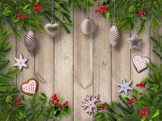 Christmas tree branches, silver decoration and gingerbread cookies on grey wooden background