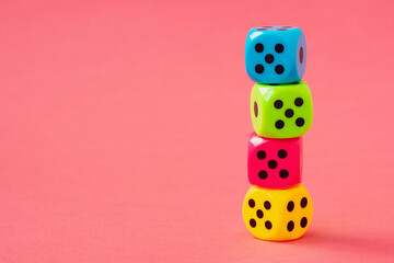 Stack of colorful dice on pink background