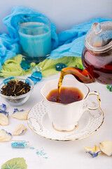 tea ceremony, kettle with brewed black tea, with rose petals, poured into a white cup