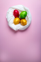 Colored eggs into a nest on a multicolored background .