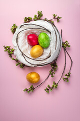Colored eggs into a nest on a multicolored background .