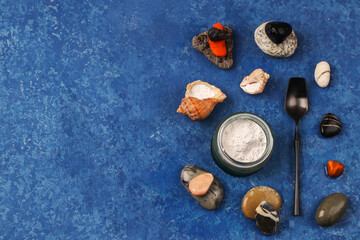 Fototapeta na wymiar Healthy lifestyle concept. Hydrolyzed marine collagen powder in a glass jar among stones on a blue background. Natural supplement. Copy space.