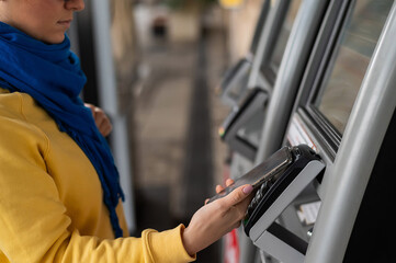 Close-up of a woman paying at a self-service machine using a contactless phone payment