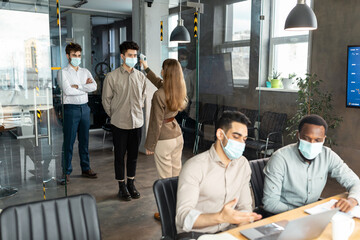 Woman with contactless thermometer measuring temperature of multiracial people