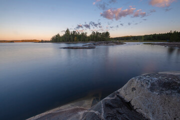 rocky shore of Lake Ladoga, Karelia, Russia with a view of the island on a summer morning. .water on long exposure.