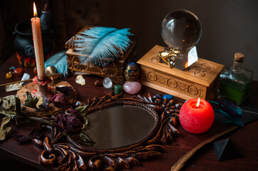 A fortune teller, witch stuff on a table, candles and fortune-telling objects. The concept of divination, astrology and esotericism
