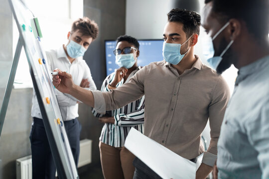 Man in protective face mask presenting business strategy on whiteboard