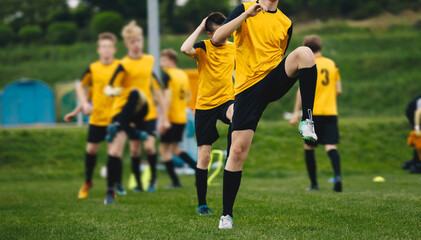 Obraz premium Group of Teenage Soccer Players on Training Session. Boys Stretching on Practice Unit Before the Game. Young Athletes Practicing Together on Grass Pitch