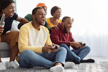 Emotional african american friends playing video games at home