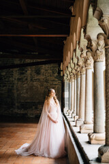 Bride stands near the columns in the balcony of an old villa on Lake Como, Italy
