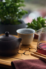 Tea ceremony gong fu cha. Handmade purple yixing zisha clay chinese teapot with shu pu erh and celadon pottery porcelain bowl with glass chahai and chaluion on bamboo teaboard tea tray or chaban.