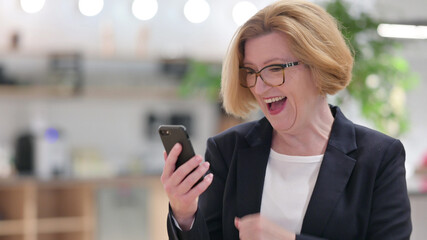 Portrait of Excited Old Businesswoman Celebrating Success on Smartphone