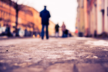Winter in a big city, a pedestrians walking along a snowy street. Close up view from the sidewalk level