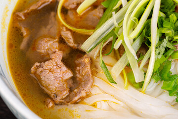 pieces of beef, with rice noodles and greens
