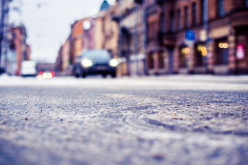 Snowy winter in the big city, the headlights of the approaching car. Close up view of a hatch at the level of the asphalt