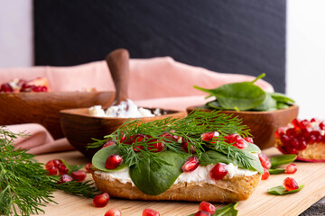 bun with healthy fresh cream, baby spinach leaves, ripe pomegranate seeds and green dill, rustic style